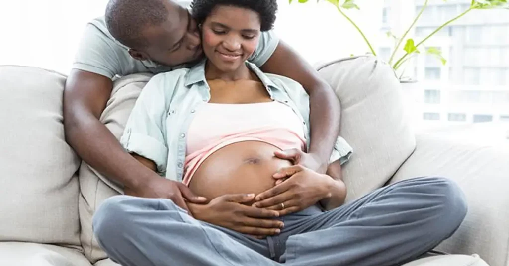 Pregnant black woman sitting with her husband on the couch.