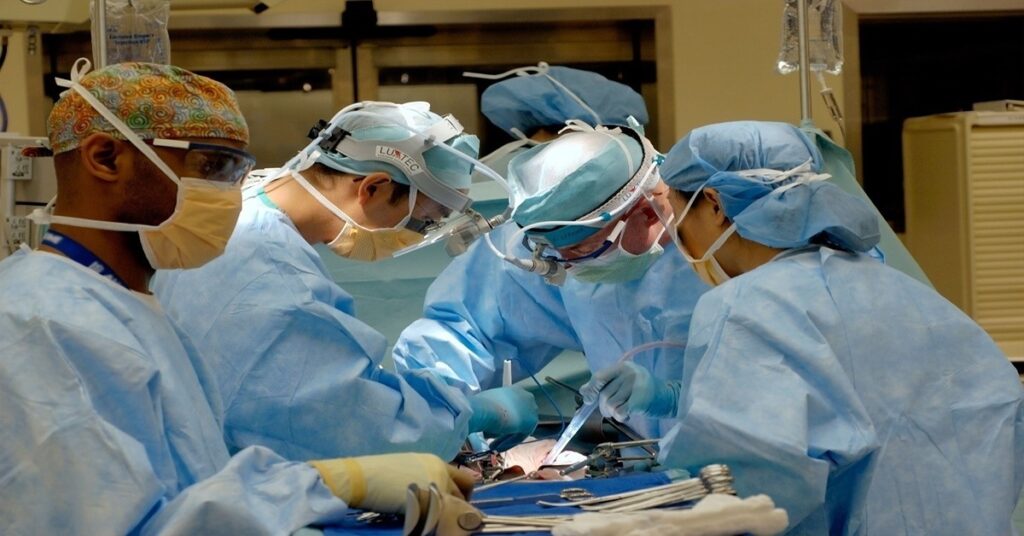 Several surgeons performing a surgery on a patient.