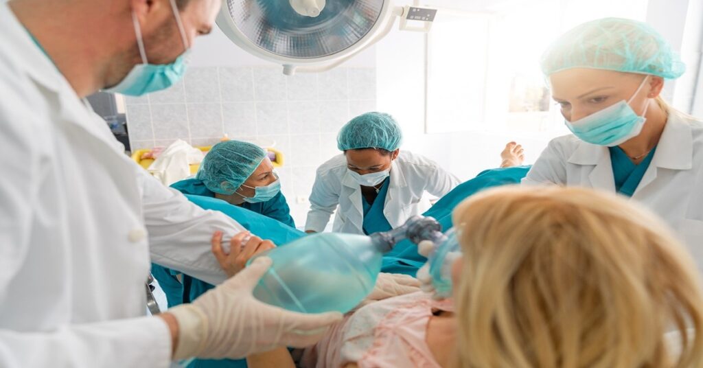Woman giving birth in a hospital surrounded by surgeons