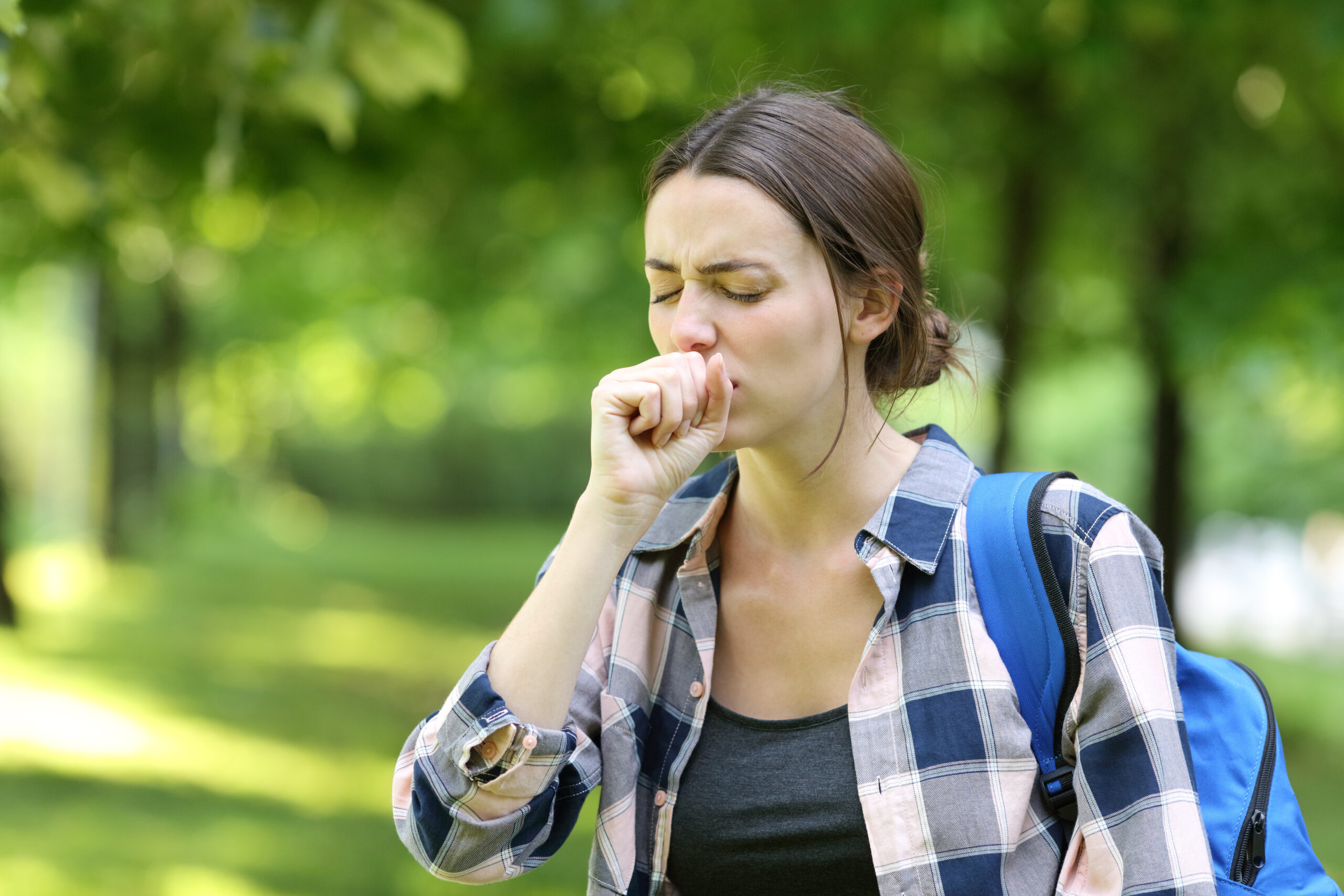 Female student coughing while walking on campus