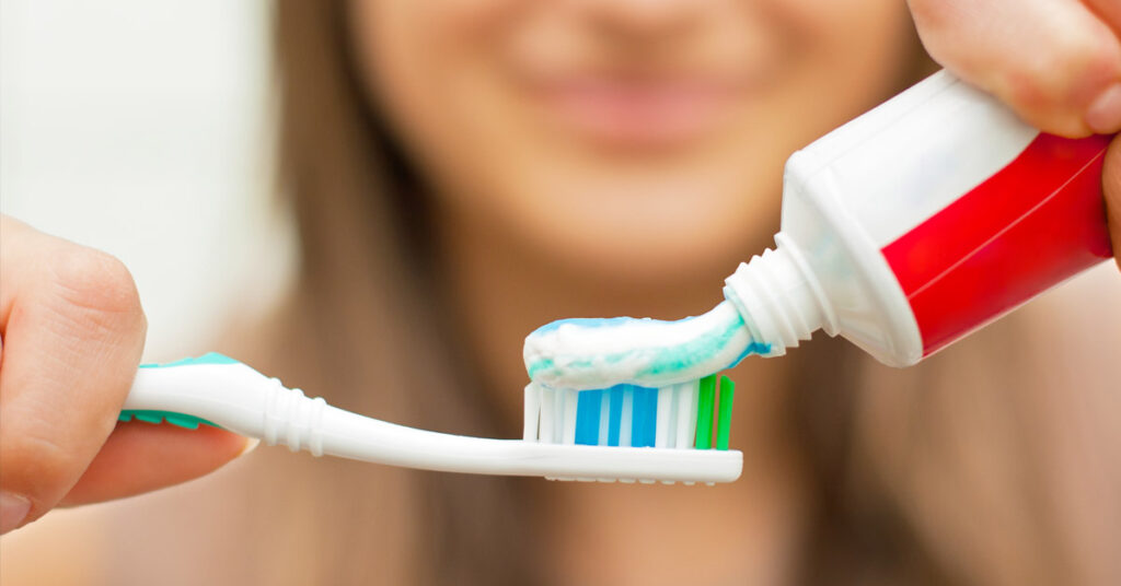 Girl putting fluoride toothpaste on a toothbrush