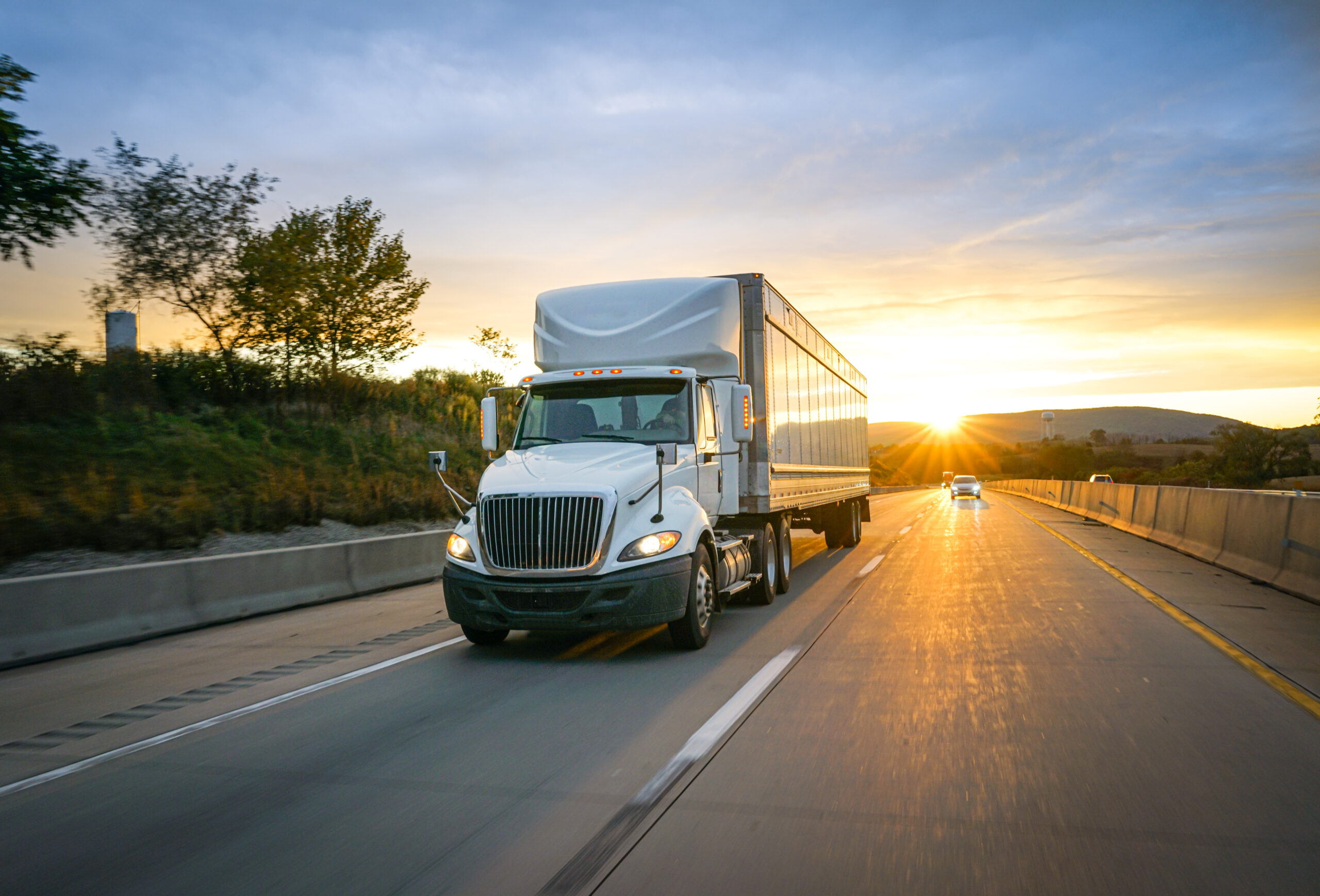 Semi truck on a highway at sunset.