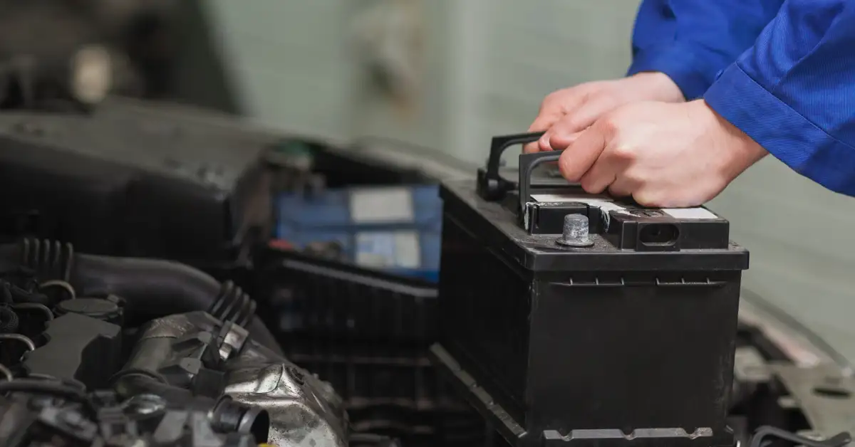 image of a man's hands removing a car battery from an engine