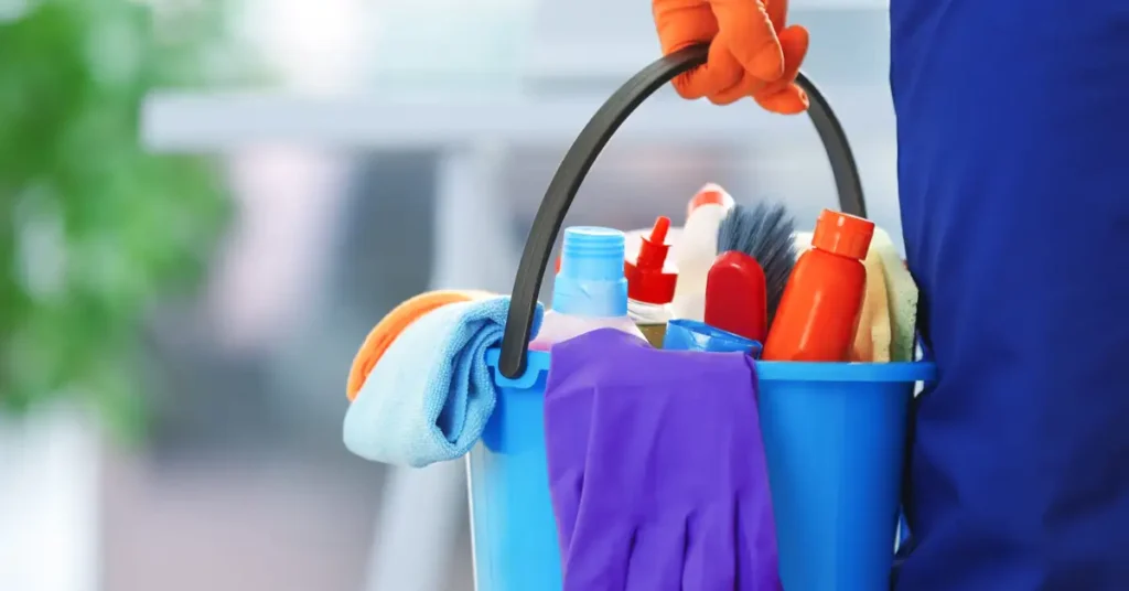 image of a person wearing a latex glove holding a bucket of cleaning supplies