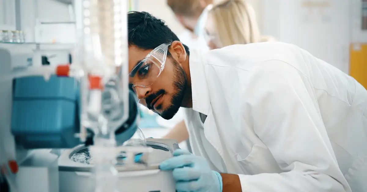 image of a male lab technician tending to a lab machine